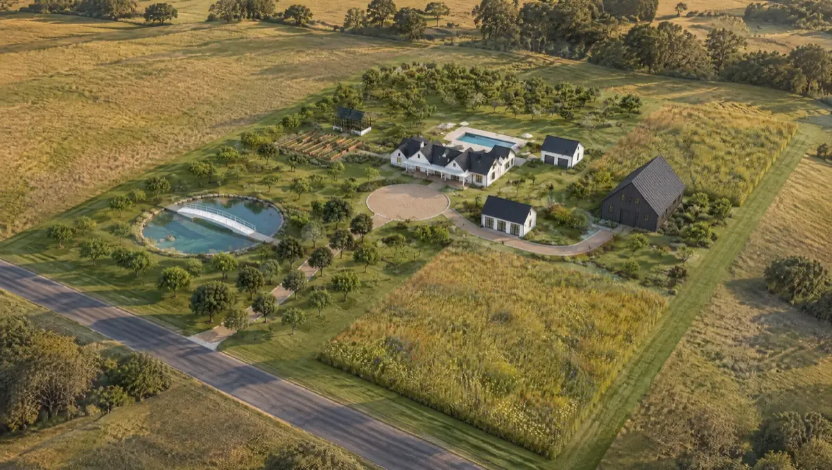 Aerial view of a modern farmhouse estate with a black barn, pond and orchard